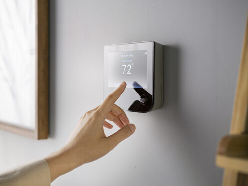 A woman adjusting the thermostat.